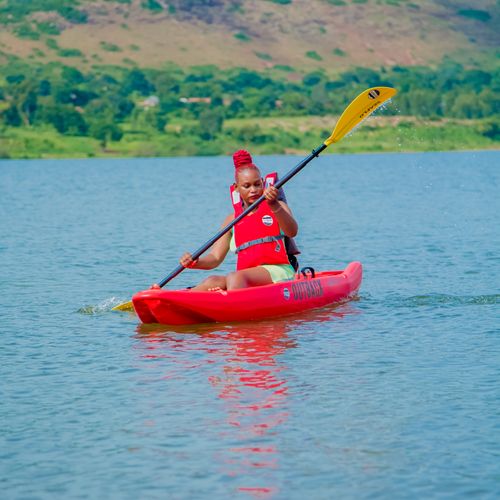 A man kayaking on a peaceful river surrounded by hills. Outdoor adventure in nature.
