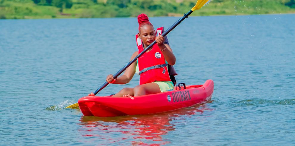 A man kayaking on a peaceful river surrounded by hills. Outdoor adventure in nature.