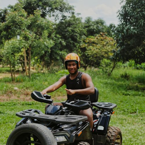 Man on a quad bike wearing a helmet in a lush rural area, showcasing outdoor adventure.