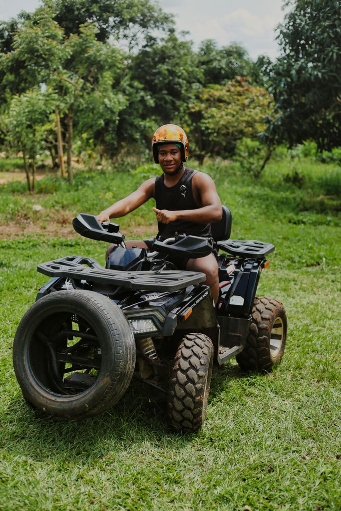 Man on a quad bike wearing a helmet in a lush rural area, showcasing outdoor adventure.