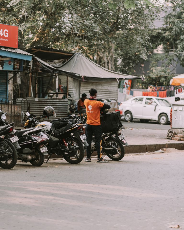 Street view of a delivery rider with motorcycles in an urban setting, showcasing local commerce.