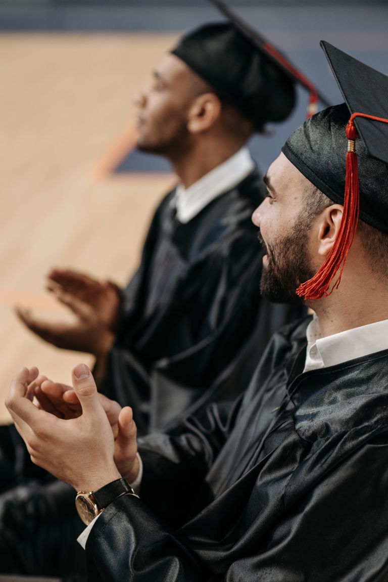 A joyful moment at a graduation ceremony with graduates clapping in their caps and gowns.