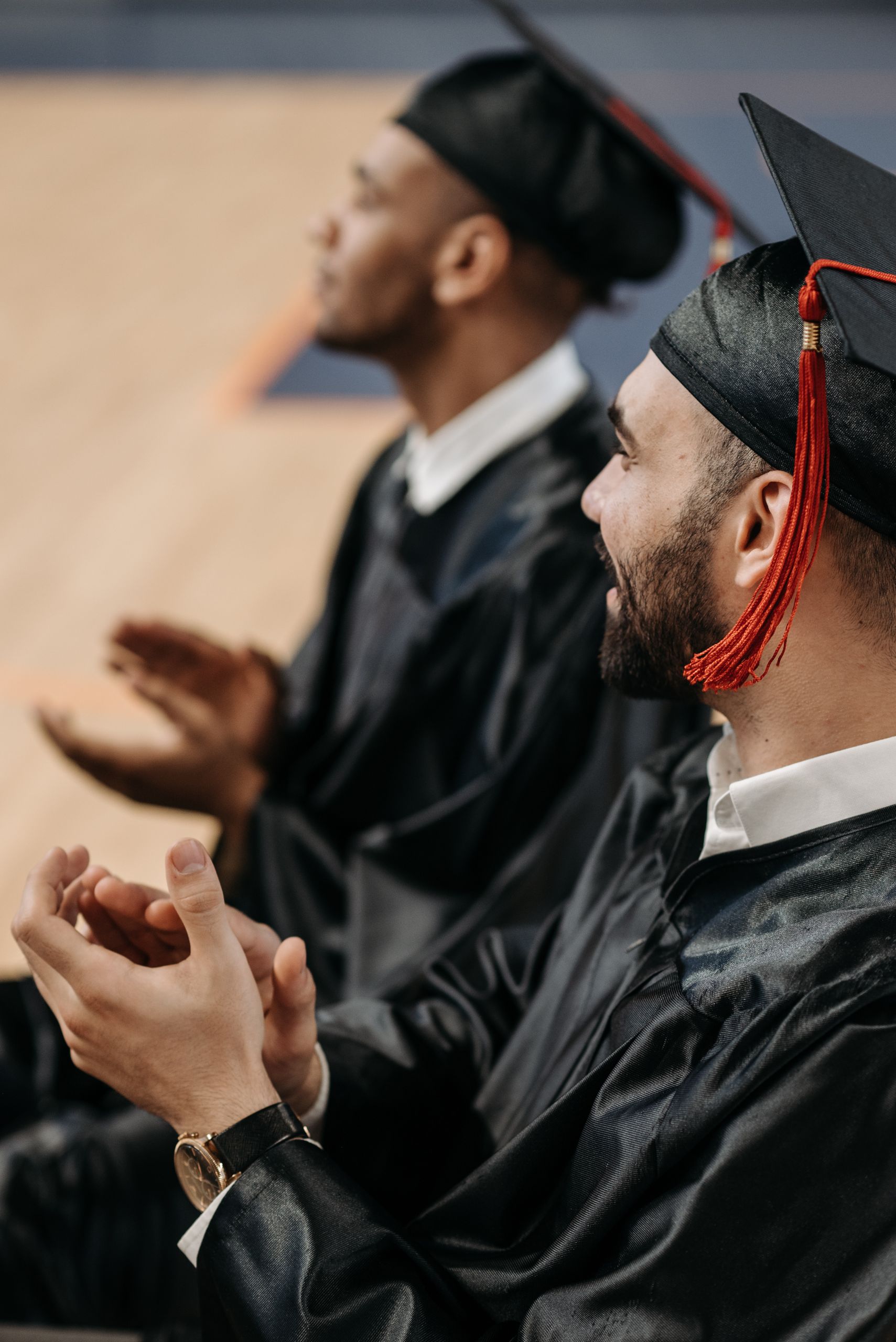 A joyful moment at a graduation ceremony with graduates clapping in their caps and gowns.