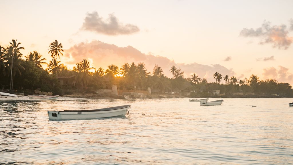 Boats drifting on the calm sea during a picturesque Zanzibar sunset.