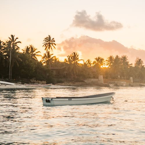 Boats drifting on the calm sea during a picturesque Zanzibar sunset.