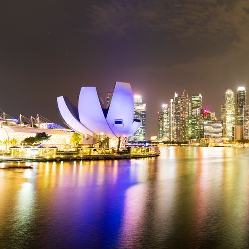 Night view of Singapore's illuminated skyline and Marina Bay Sands, reflecting vibrant city lights.