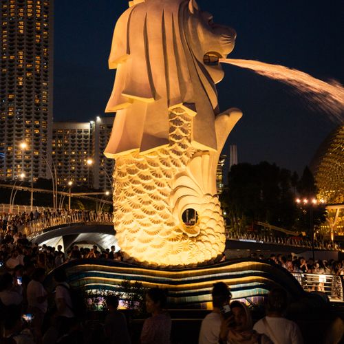 Vibrant night scene of the iconic Merlion statue in Singapore with cityscape.